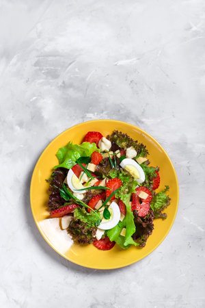 Salad from strawberry, cheese, and greens. Salad on a yellow plate.の写真素材