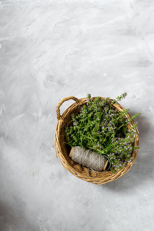 fresh thyme with fragrant flowers collected. on a gray background. in a wicker basket.の写真素材