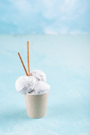 Vanilla ice cream in a paper cup on a blue, turquoise and purple background. With sweets and decorative sweet decorations.の写真素材