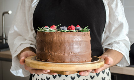 Girl cook holds a chocolate dessert with sugar-free berries in her hands. Close-up