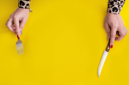 Top view girl holding a fork and knife on a yellow background