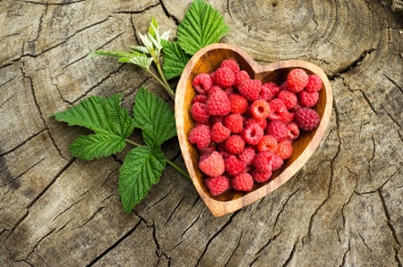 red raspberries in a heart on the background of the stumpの写真素材