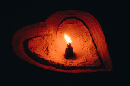 Lighting from oil lamp with heart shaped lantern base, Arts from a pile of sand.の写真素材