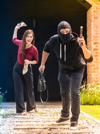 Beautiful woman throwing her shoes to the thief, who stole her handbag and running away. Selective focus. Threatening situation concept.の写真素材