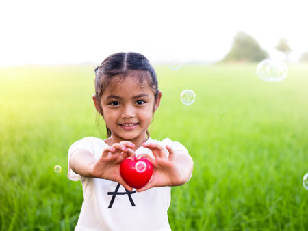 Happy little asian girl holding red heart and smiling.の写真素材