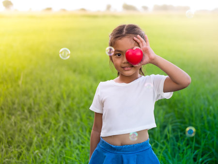A little asian girl closed her eye with a red heart. The eyes're the window of the soul concept.の写真素材