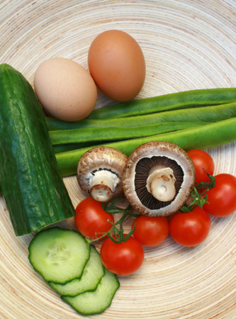 Salad ingredients set on a oval wooden platter.Tomato,mushroom,beans,cucumber and eggs.の写真素材