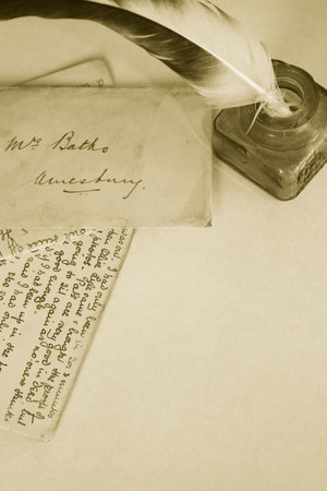 Sepia toned image of an ink pot with feathered quill and hand written letters (recreated by self). Portrait format.の写真素材