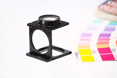 A printers eye glass on a white isolaed background with a colour swatch book.の写真素材