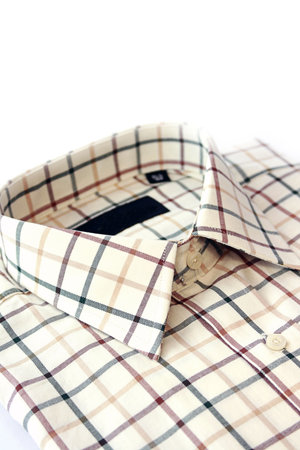 A close up view of a mans green, burgundy and yellow cotton checked shirt. Room for copy above.