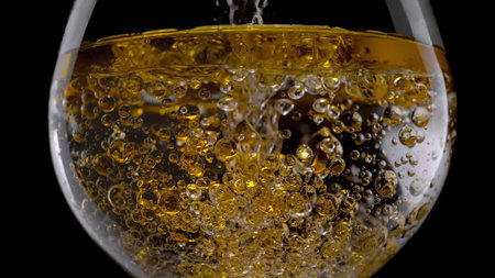 A glass with a drink on a black background. A drink is poured into the glass. Cold fizzy drinkの写真素材
