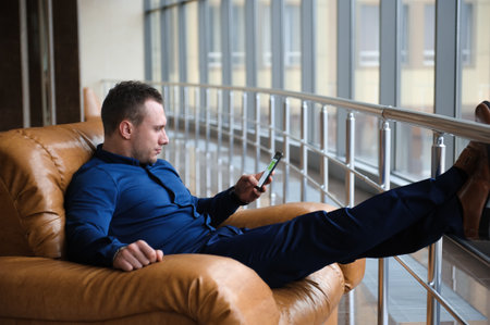businessman looking through the phone by the window
