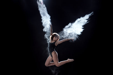Girl dancing with a flour on the black background on the sceeneの写真素材