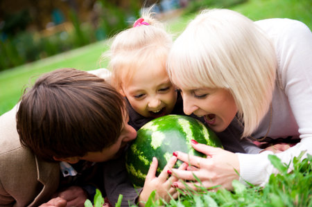 Family is eating a watermelon together in the park.の写真素材