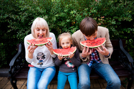 Family is eating a watermelon together in the park.の写真素材
