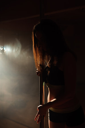 Close up of young slim female body near the pole.
