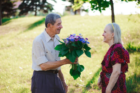 An elderly man of 80 years old gives flowers to his wife