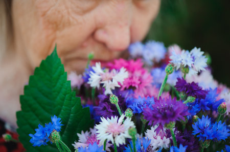 Elderly grandmother with a bouquet of flowers in the park