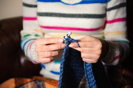 Close-up of woman hands knitting colorful wool yarn.