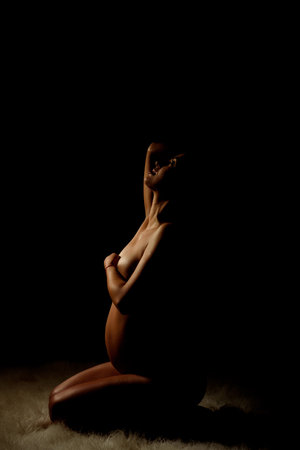 Happy pregnant woman over dark background, isolated silhouetteの写真素材