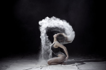 Girl dancing with a flour on black background.の写真素材