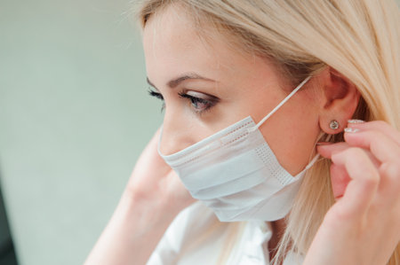 adult dentist puts a protective mask on her mouth.の写真素材