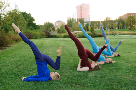 a group of adult women attending yoga outside in the parkの写真素材