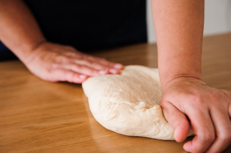 Cook hands kneading dough, sprinkling piece of dough with white wheat flour.の写真素材