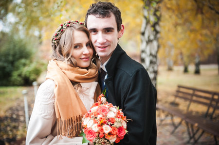 newlyweds in a coat and scarf on a cold autumn day in the park.の写真素材