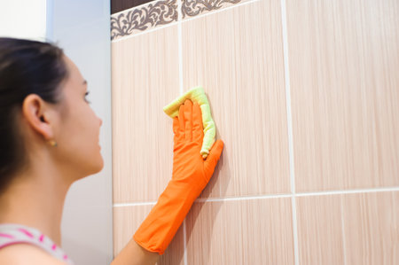 A woman washer is cleaning tiled surface in bathroom.の写真素材