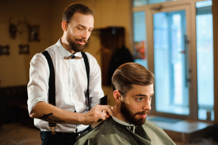 Master cuts hair and beard of men in the barbershopの写真素材