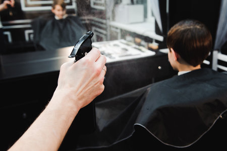Young handsome barber making haircut of cute boy in barbershop.の写真素材