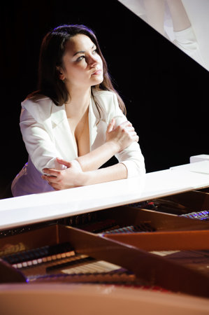The woman with white piano. Beautiful pianist on the stage near the piano.の写真素材