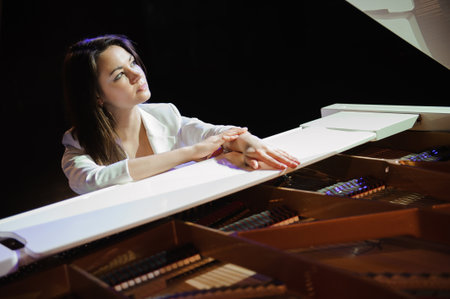 The woman with white piano. Beautiful pianist on the stage near the piano.