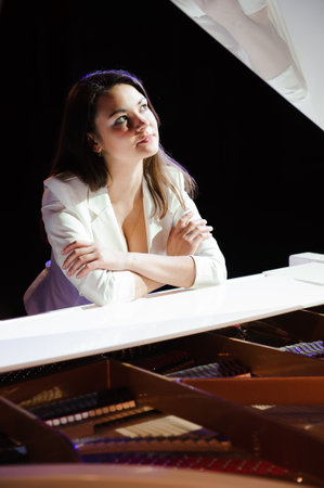 The woman with white piano. Beautiful pianist on the stage near the piano.の写真素材