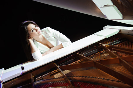 The woman with white piano. Beautiful pianist on the stage near the piano.の写真素材