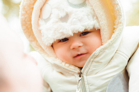 Mother and father with baby dressed in warm clothes walking on a sunny day outdoors. Happy family...