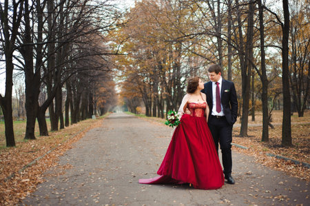 happy bride and groom walking in the autumn forestの写真素材