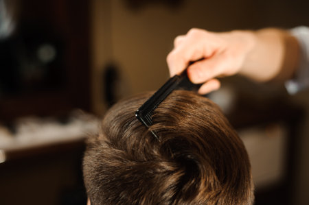 Master cuts hair and beard of men in the barbershop, hairdresser makes hairstyle for a young manの写真素材