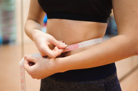 Young slim woman measuring waist using the tape measureの写真素材