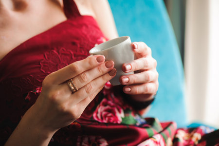 Close up of beautiful female hands holding white cup of coffee.の写真素材
