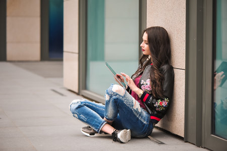 Youth and technology. Attractive young woman using tablet computer outdoors.