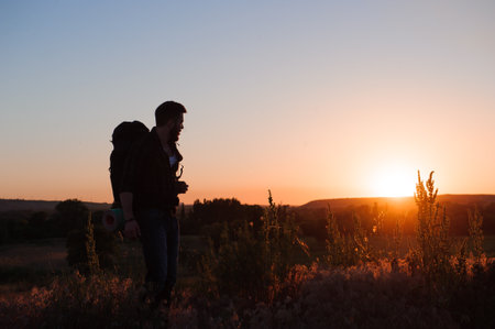 Traveler with backpack standing on a rock and enjoying sunset.の写真素材
