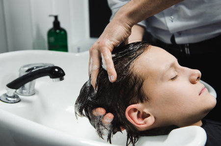 a boy is washed by the hairdresser in the barbershop.の写真素材