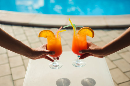 Bikini women in pool relaxing with juice, young beautiful sexy girls resting in vacation on summer...