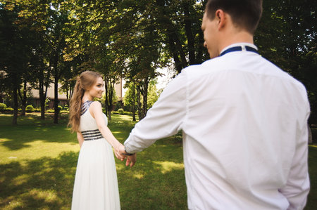 Couple in wedding attire is in the hands against the backdrop of the field at sunset, the bride and groomの写真素材