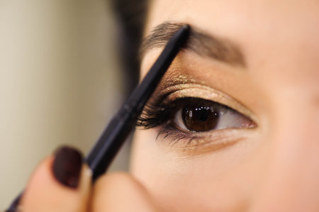 Beautiful brunette woman paints the eyebrows. Beautiful woman face. Makeup detail. Beauty girl with perfect skin.の写真素材