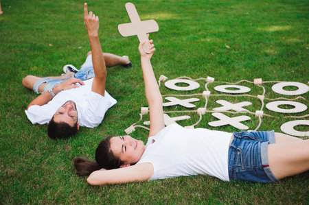 Friends rest and play tic-tac-toe. Game on green grass