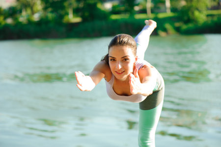Beautiful young woman meditating in yoga pose at a mountain streamの写真素材
