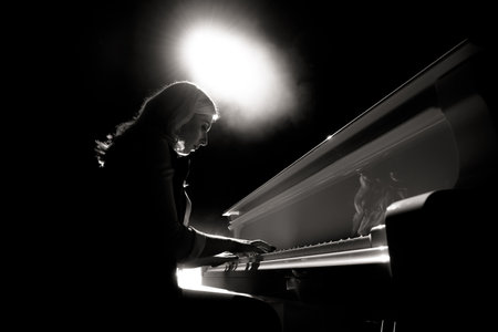 Close up view of a girl plays piano in the concert hall at the sceneの写真素材